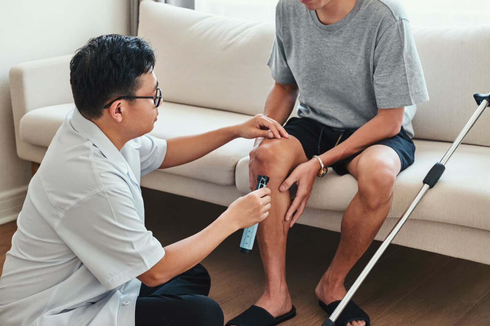 A physiotherapist measuring a patient's knee movement at home after surgery