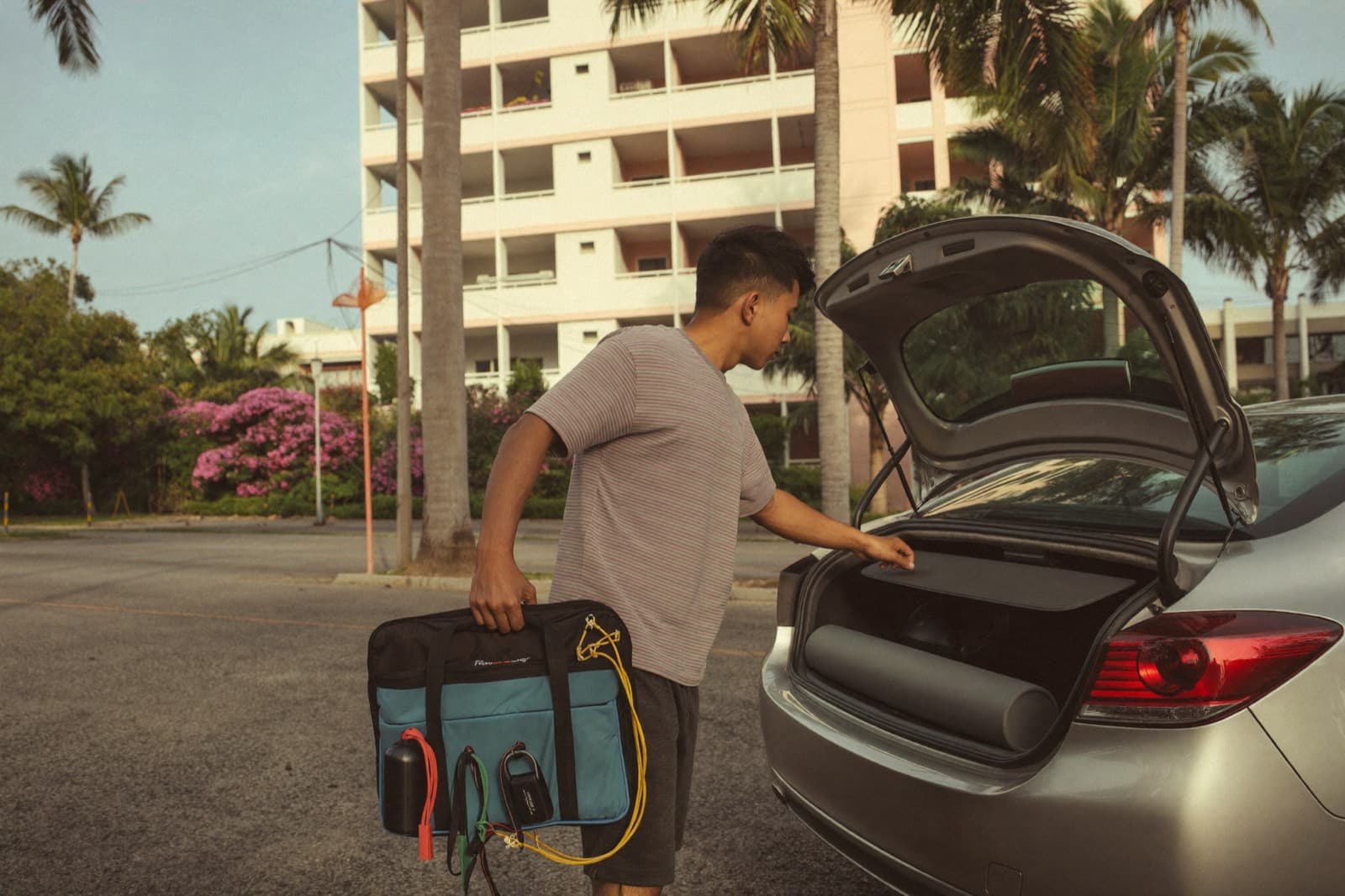 A physiotherapist loading his equipment bag into his car before a home visit