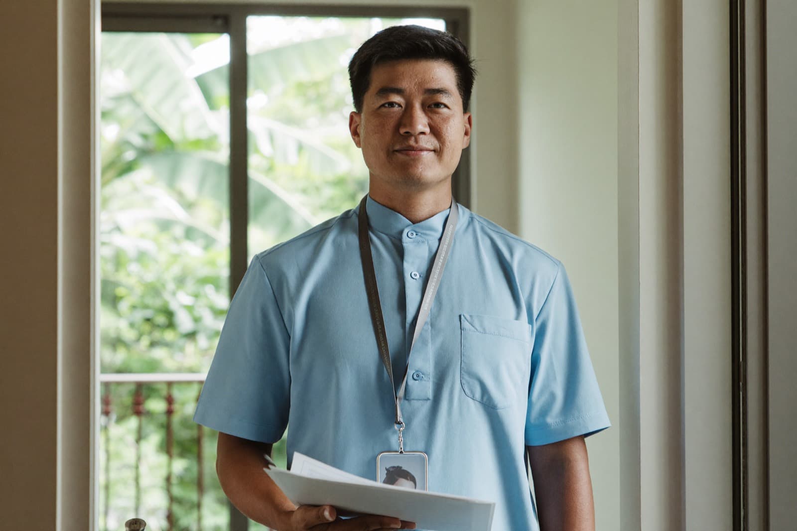 A physiotherapist holding his registration documents in a doorway